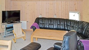 A living room with a leather sofa, a wooden coffee table, a television on a stand, and a chair. - Amazing home in ålbæk with WiFi (Ålbæk)