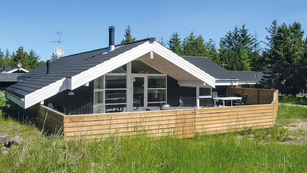 A modern house with a sloped roof, large windows, and a wooden deck. - Amazing home in ålbæk with WiFi (Ålbæk)