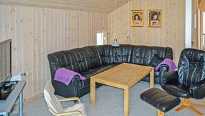 A cozy living room with a black leather sofa, a wooden coffee table, and a black leather armchair. There are two framed pictures on the wall. - Amazing home in ålbæk with WiFi (Ålbæk)