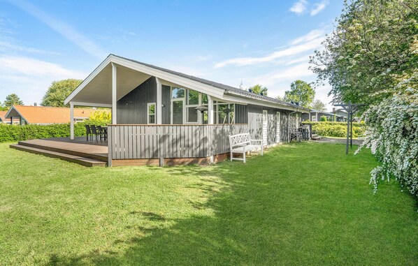 A modern house with a covered porch, a small deck, and a well-maintained lawn.