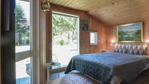 A bedroom with a large bed, a window, a painting, and a small table with a lamp. - Gorgeous home in Spøttrup (Spøttrup)