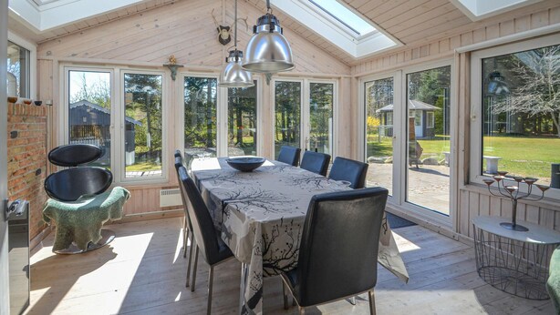 A sunroom with a large table and chairs, large windows, and a view of the outdoors. - Gorgeous home in Spøttrup (Spøttrup)