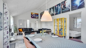 A modern living room with a dining area, a yellow bookcase, and movie posters on the wall. - Amazing home in Oksbøl with sauna (Oksbøl)
