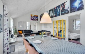 Ein modernes Wohnzimmer mit Essbereich, einem gelben Bücherregal und Filmplakaten an der Wand.