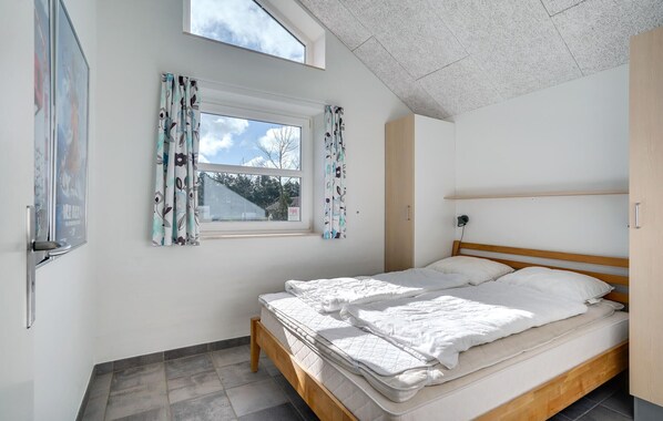 A bedroom with a bed, a window with curtains, a ceiling with a textured pattern, and a door. - Amazing home in Oksbøl with sauna (Oksbøl)
