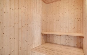 Una sauna in legno con una panca e uno scaffale.