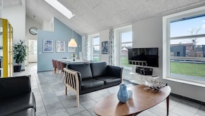 A modern living room with a black leather sofa, a wooden coffee table, and a TV mounted on the wall. - Amazing home in Oksbøl with sauna (Oksbøl)