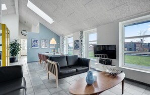 Een moderne woonkamer met een zwarte leren bank, een houten salontafel en een aan de muur bevestigde televisie.
