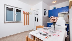 A small kitchen with blue cabinets, a white refrigerator, and a dining table set with plates and a vase of flowers. - Stunning apartment in Pula with WiFi (Pula)