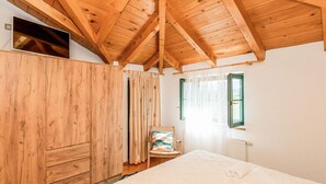 A bedroom with a wooden ceiling, a bed, a chair, a wardrobe, and a window. - Beautiful home in Prolozac Donji (Prolozac Donji)