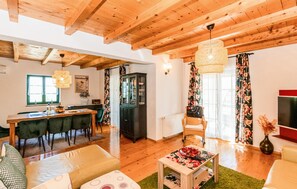 Un vaste espace de vie doté d’un plafond en bois, d’une table à manger avec des chaises, d’un canapé, d’une table basse et d’un meuble de rangement.