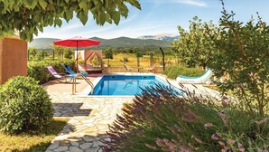 A pool area with a stone pathway, lounge chairs, a red umbrella, and a view of mountains. - Beautiful home in Prolozac Donji (Prolozac Donji)