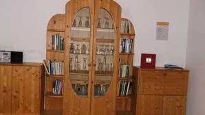 Un armari de fusta amb portes de vidre, que conté llibres i objectes de vidre.