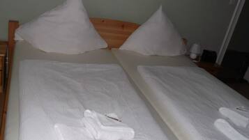 Ein Doppelbett mit weißen Bettwäsche und Kissen, ein Holz-Kopfstück und ein Nachttisch mit Lampe und Telefon.