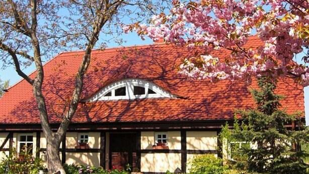A traditional building with a red-tiled roof, a prominent window, and a well-maintained garden with statues. - Apartment 1 - Rügen apartment 119 (Garz/Rügen)