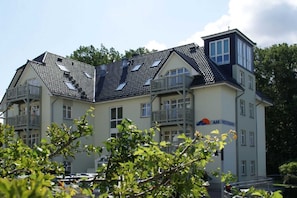 A multi-story building with a sloped roof, balconies, and a sign indicating it is a Weststrand hotel.