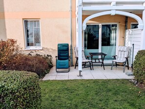 A patio area with a blue chair, two striped chairs, and a table. - (193) 2-room apartment - apartment house Baltic Sea beach (Kühlungsborn)