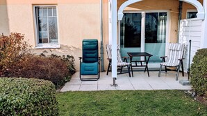 Un espace patio avec une chaise bleue, deux chaises à rayures et une table.