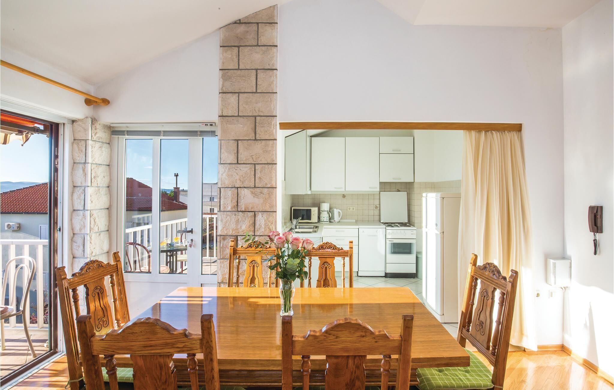 Un comedor con una mesa y sillas de madera, una pared de piedra y vistas al exterior.