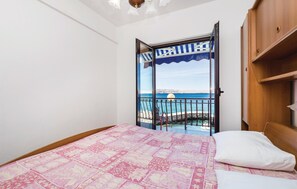 Un dormitorio con cama, un armario de madera y un balcón con vista al mar.