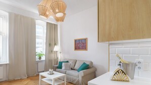 Una sala de estar moderna con sofá, una mesa de centro, una lámpara y una zona de cocina con encimera y cubo para vino.