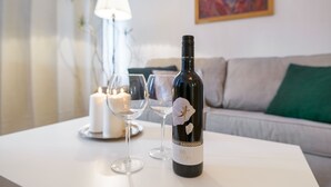 Una botella de vino sobre una mesa con dos copas y una vela.