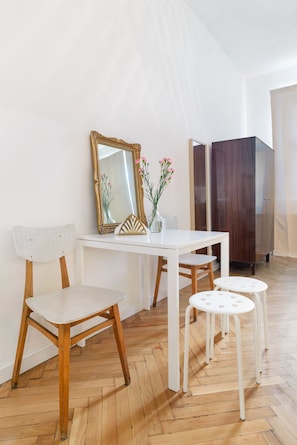 Una habitación con una mesa blanca, dos sillas, un espejo y un armario.
