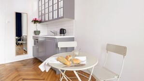 Cocina compacta con comedor, que incluye una mesa con pan y un cuchillo, una silla y una planta en maceta.