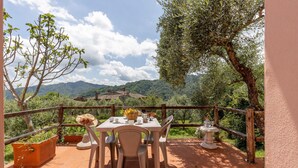 An outdoor dining area with a table set for two, surrounded by a wooden fence, overlooking a mountainous landscape. - Awesome home in Borgo a Mozzano LU (Borgo a Mozzano LU)