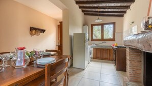 A kitchen with a wooden table, chairs, a refrigerator, a washing machine, a window, and a brick oven. - Awesome home in Borgo a Mozzano LU (Borgo a Mozzano LU)