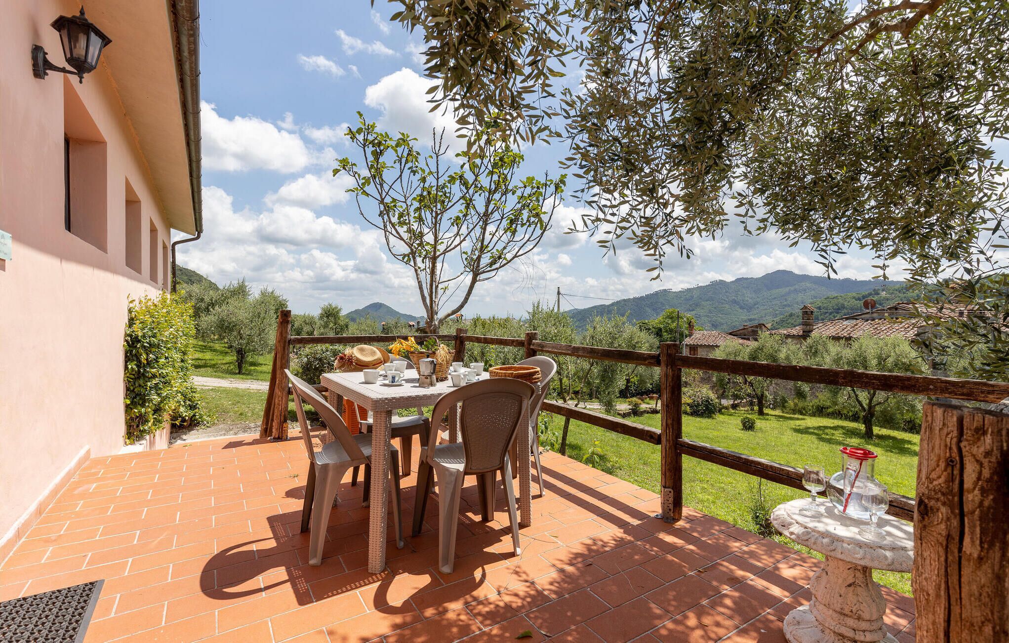 Une terrasse avec une table et des chaises, offrant une vue panoramique sur un paysage magnifique, avec des montagnes et une végétation luxuriante.