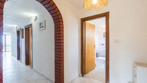 A hallway with a brick column, white walls, and a wooden door leading to a bathroom. - 2 bedroom pet friendly apartment in Zbandaj (Zbandaj)