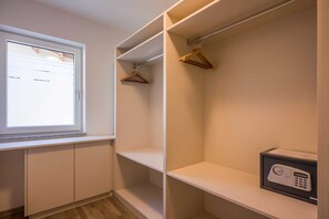 A walk-in closet with a window, wooden hangers, and a safe.