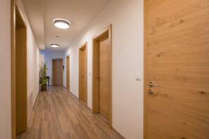 A hallway with wooden doors, a potted plant, and recessed ceiling lighting. - Apartment Dorfplatzl - Aparthotel **** AlpTirol (Kaltenbach)