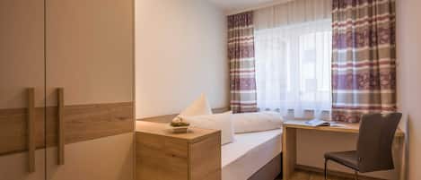 Un dormitorio con cama, escritorio, silla y armario.