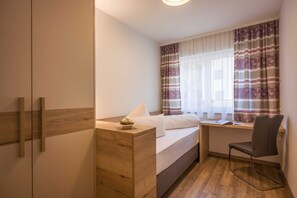 A bedroom with a bed, a desk, a chair, and a wardrobe.