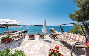 A stone patio with outdoor seating, a white umbrella, and a view of the sea. - 2 bedroom stunning home in Brodarica (Brodarica)
