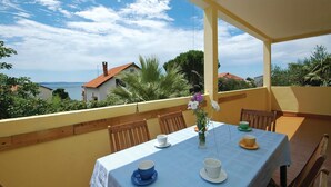 Varanda com mesa posta para chá, com vista para a costa, casas e vegetação.