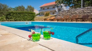 Uma piscina com dois copos de líquido verde e cerejas na borda.