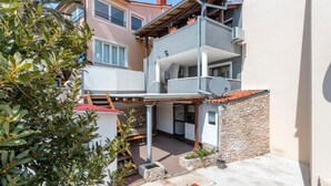 Un edificio residencial de varios pisos con balcones, una antena parabólica y un muro de piedra.