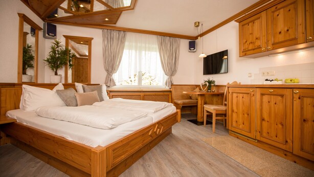Ein Schlafzimmer mit einem hölzernen Bett, einem Schreibtisch und einem Fernseher.