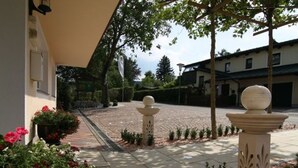Un patio con un sendero empedrado, pilares de piedra decorativos y plantas en macetas.