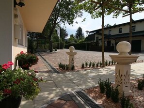 A courtyard with a paved walkway, decorative stone pillars, and potted plants. - FEWO 3 - de luxe - Pension KNOLL am Attersee (Schörfling am Attersee)