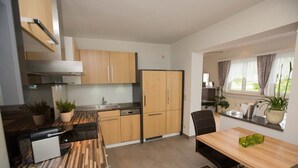 Una cocina moderna con armarios de madera, una mesa de comedor con sillas y una ventana con cortinas.