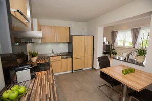 Una cocina moderna con armarios de madera, una mesa de comedor con sillas y una ventana con cortinas.