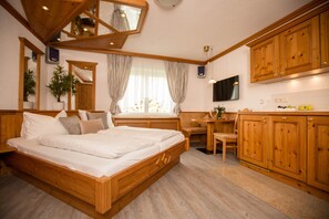Ein Schlafzimmer mit einem hölzernen Bett, einem Schreibtisch und einem Fernseher.