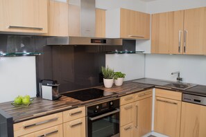 Une cuisine moderne avec des meubles en bois, un four encastré, un lave-vaisselle et une machine à café.