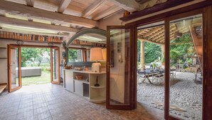 A spacious room with a tiled floor, a wooden ceiling, and a large sliding glass door leading to an outdoor area with a table and chairs. - Gorgeous home in Barbarano Vicentino VI (Barbarano Vicentino VI)