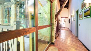 A hallway with wooden flooring, stone walls, and large windows with a view of greenery outside. - Gorgeous home in Barbarano Vicentino VI (Barbarano Vicentino VI)