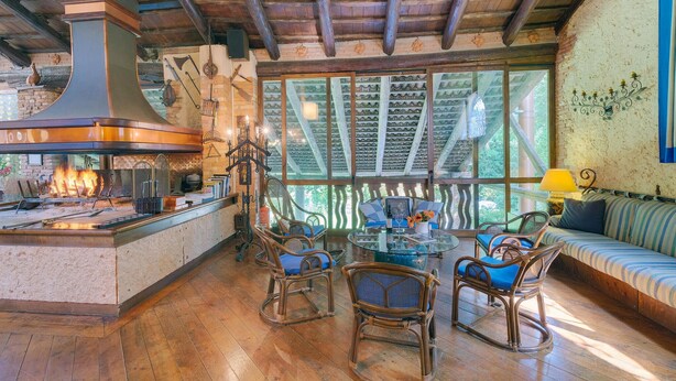 A rustic kitchen with a wood stove, wicker chairs, and a glass table. - Gorgeous home in Barbarano Vicentino VI (Barbarano Vicentino VI)